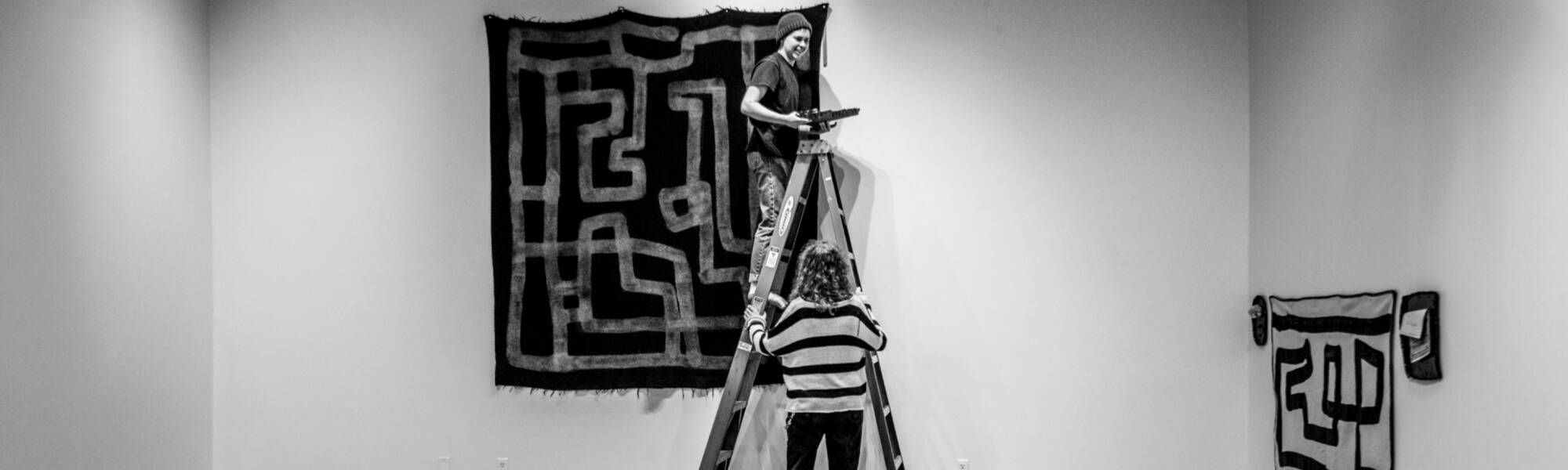 First-year history and art history student, Taylor Braman, below, and Blake Matthews ’22, on ladder, works with guest artist Emmy Bright’s exhibit “Everybody Knows This is Nowhere” in the Stuart B. and Barbara H. Padnos Student Gallery January 9.